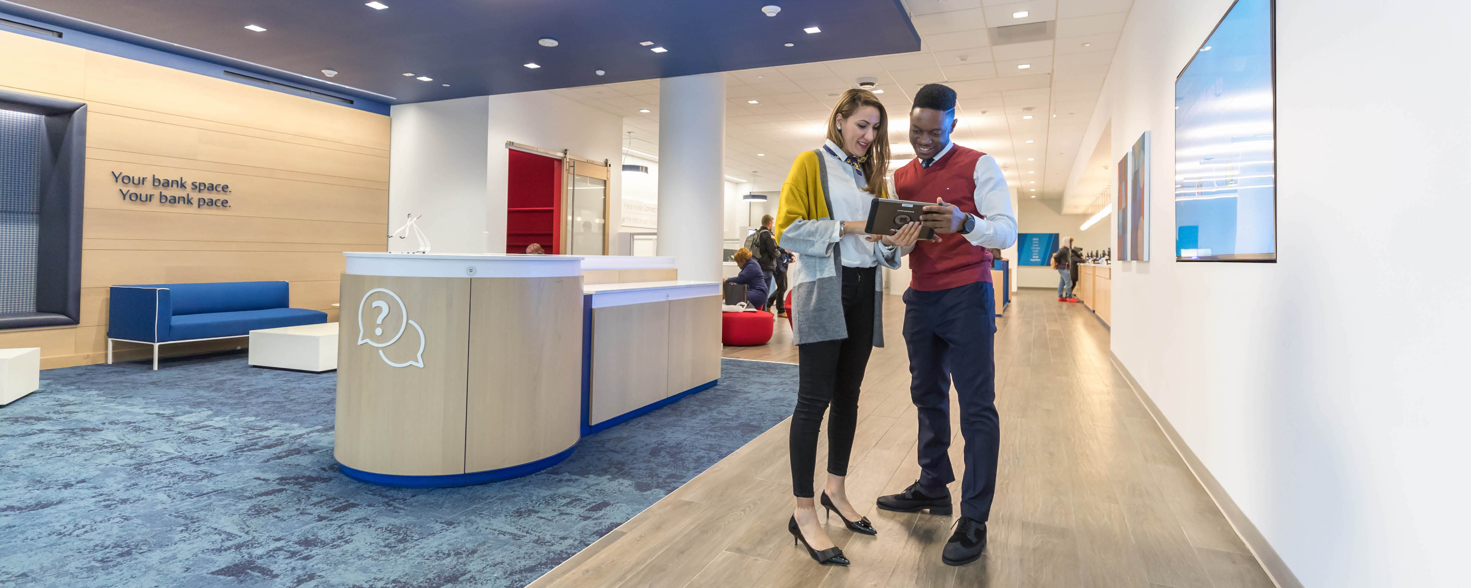 Two Capital One Cafe Ambassadors stand in a Capital One Cafe looking at an iPad